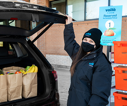 Picture of a woman keeping the groceries in a car trunk to set it off for delivery.