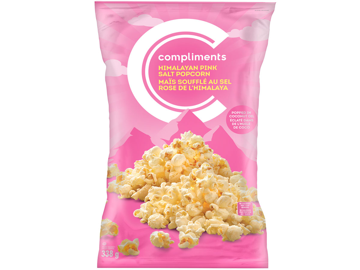 Pink bag of Compliments Himalayan Pink Salt Popcorn mounded over an illustration of the Himalayan mountain range on package.