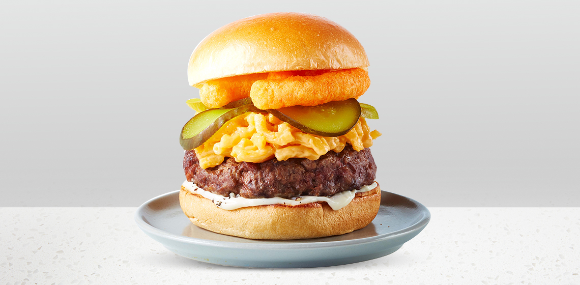 Triple Mac & Cheeseburger: brioche bun, Compliments Cheddar & Bacon Stuffed Beef Burger, Compliments Macaroni & Cheese, Cheetos, and bread and butter pickles.