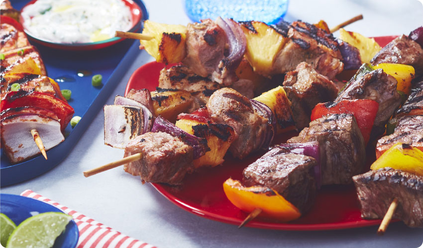 Table with three platters of barbecue skewers and meat kabobs inspired by world flavours