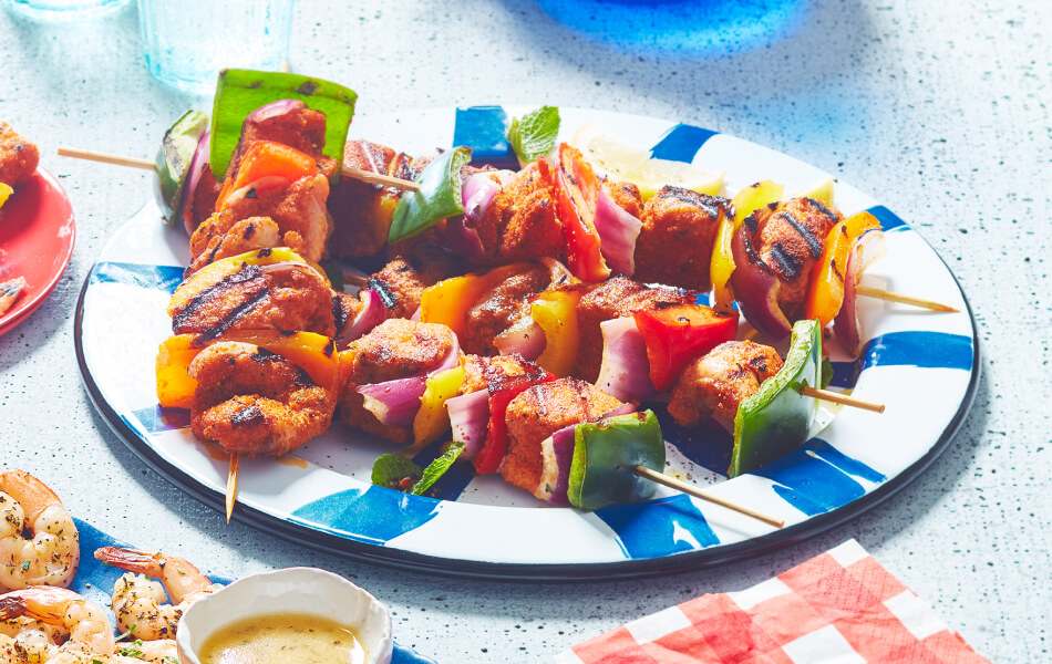 Blue and white plate with salmon and vegetable kabobs stacked on top