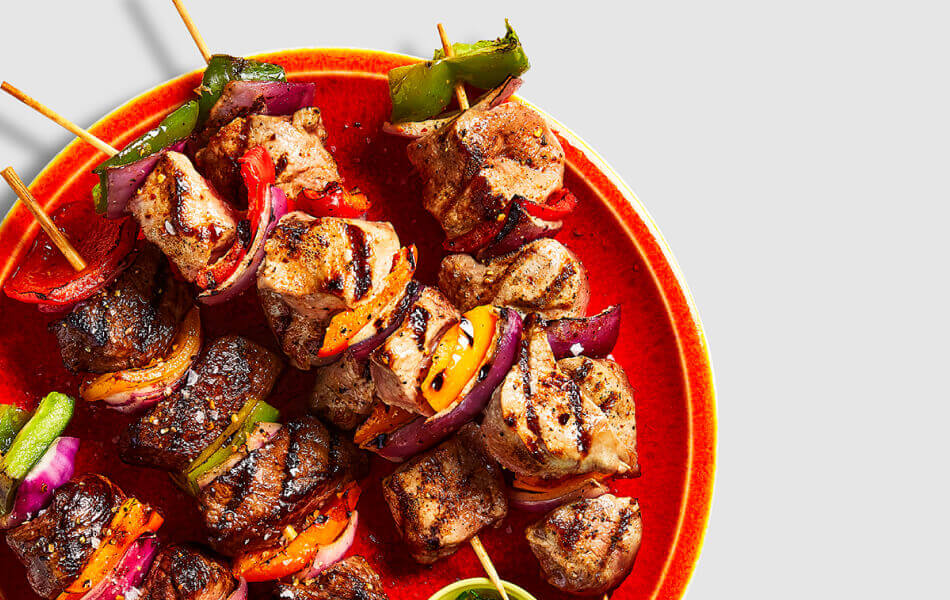 Pork and beef kabobs on a red plate.