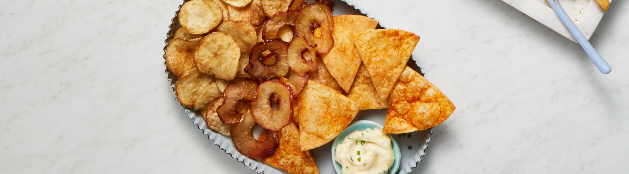 Blue serving platter with three types of chips: apple, tortilla and potato.