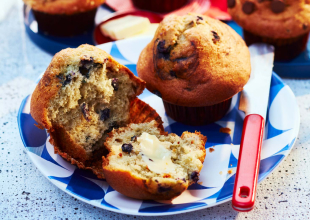 Strawberry, blueberry and chocolate chip muffins on a white and blue–patterned plate.