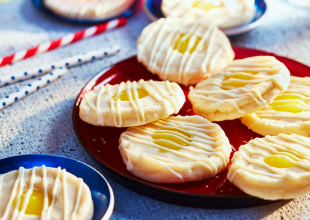Round thumbprint-style cookies with lemon pie filling sitting on a red plate.