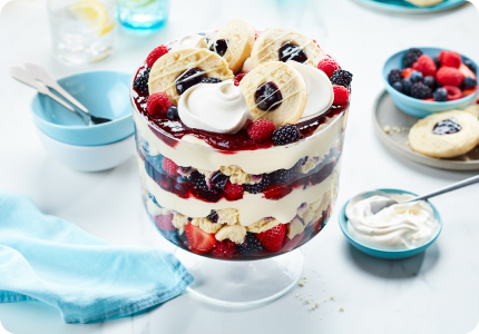 large trifle dish with layers of vanilla pudding, crumble and whole blueberry sugar cookies, fresh berries and whipped cream