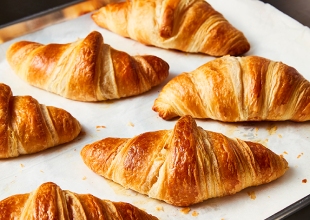 â€¯counter with parchment-lined cookie sheet of freshly baked butter croissants