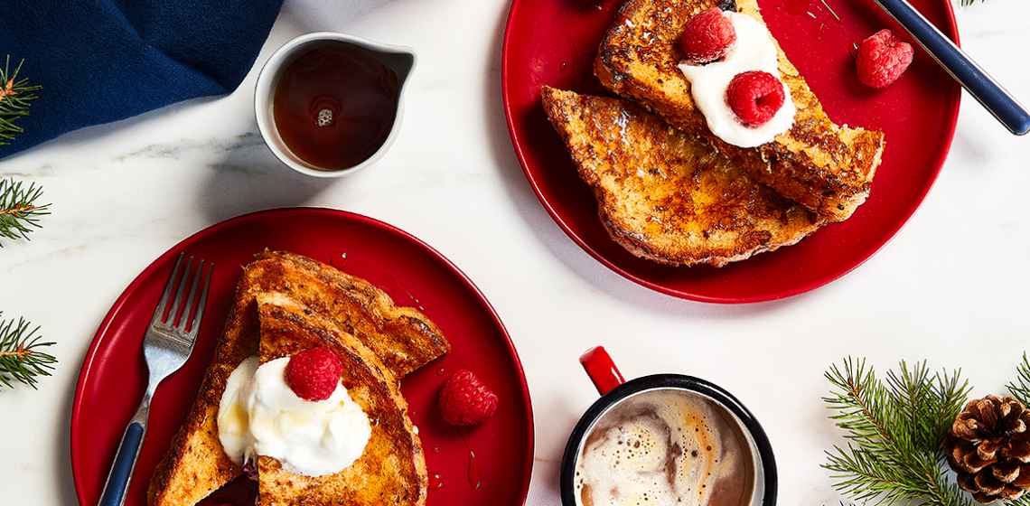Red plates on a holiday table with a stuffed eggnog French toast