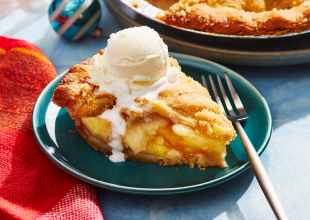 Compliments apple pie with slice taken out and topped with ice cream