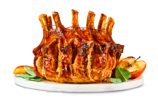 Pork crown roast sitting on a plate with halved and quartered apples and some herb leaves