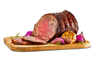 Cook prime rib roast on a wooden cutting board with roasted garlic, onions, and sprigs of rosemary